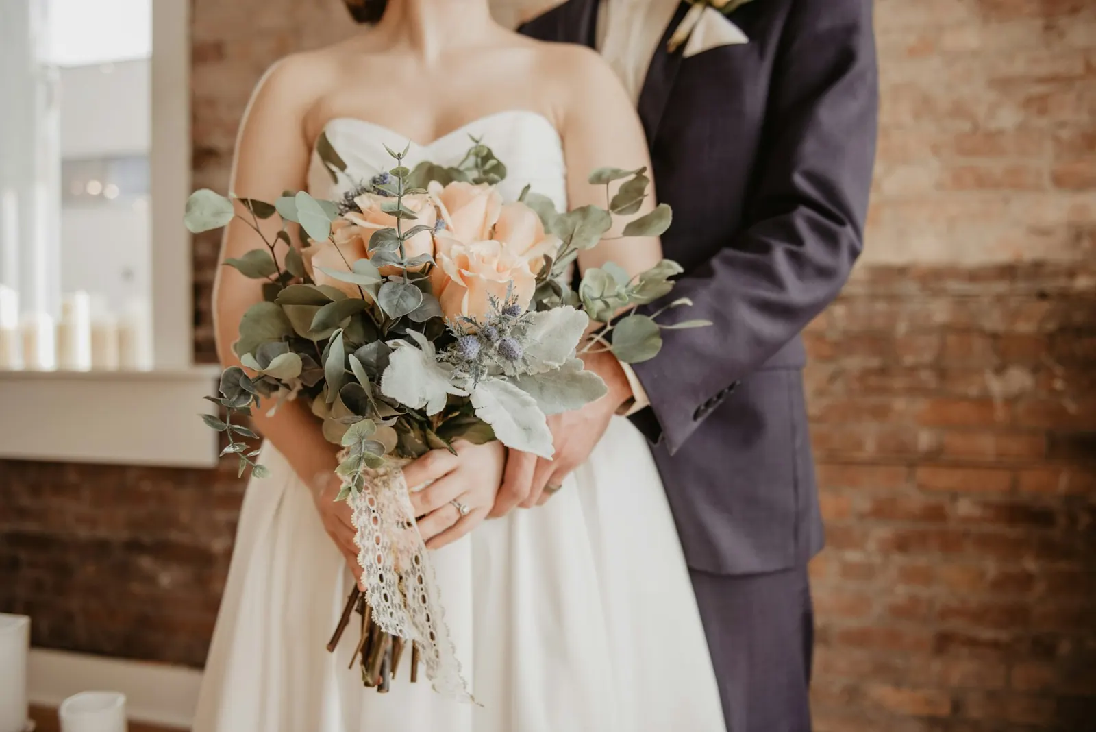 Bride holding a loose garden bouquet of peach roses and greenery