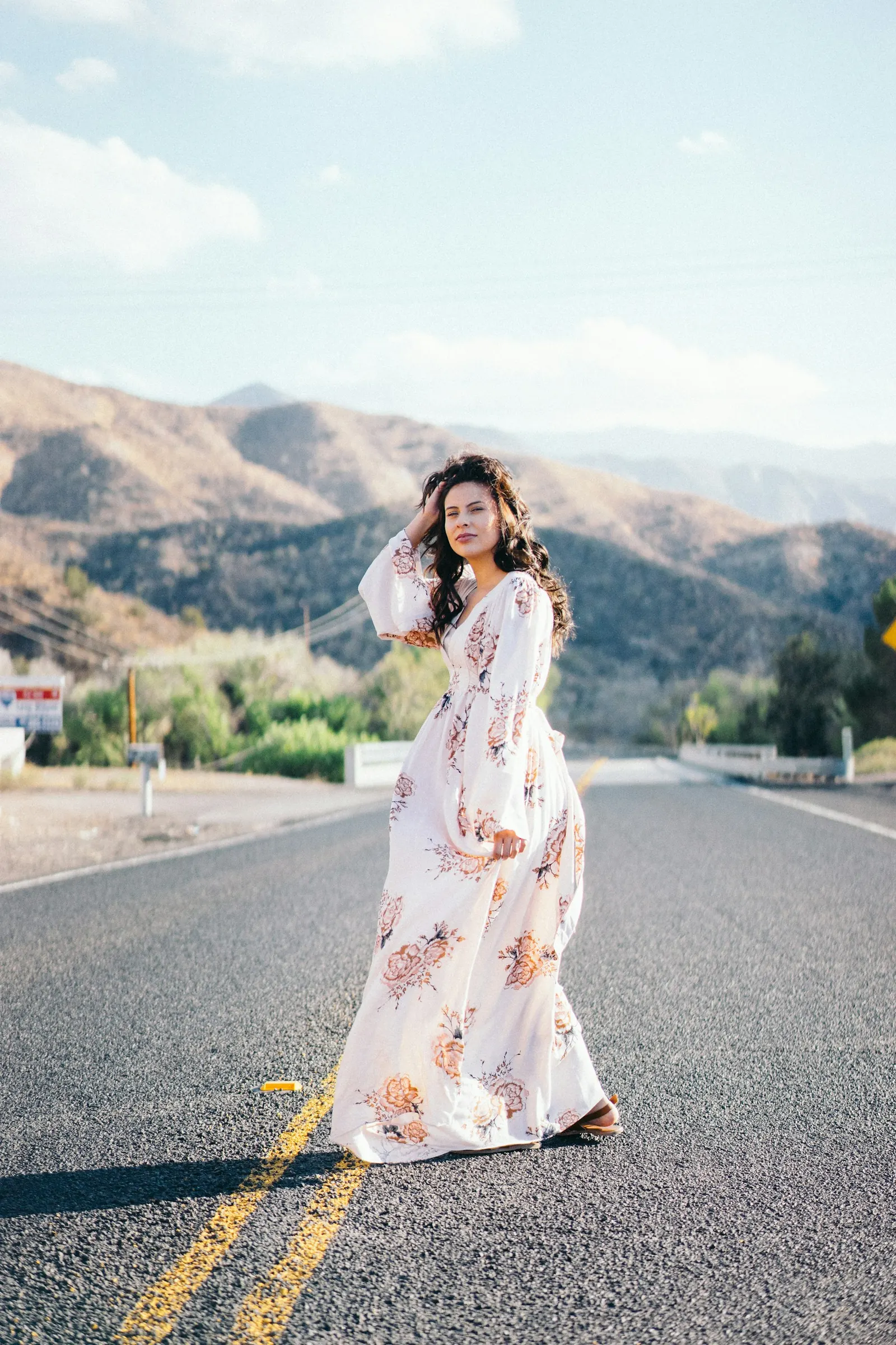 Bride in a floral gown standing on an open desert road